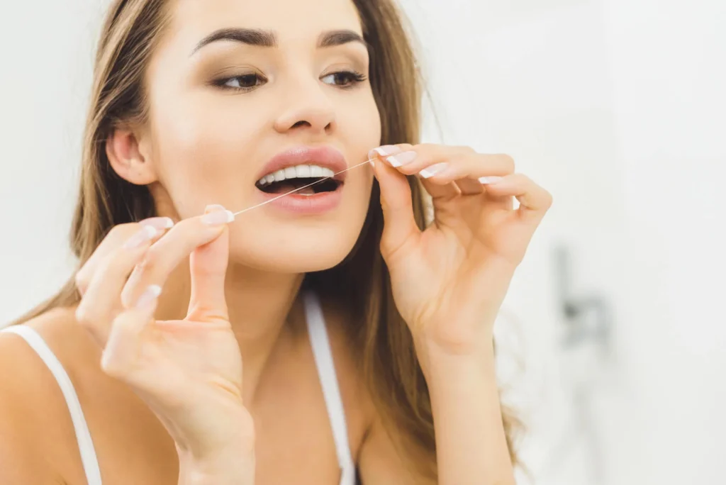 Woman flossing teeth at home dentist in Bay County, FL